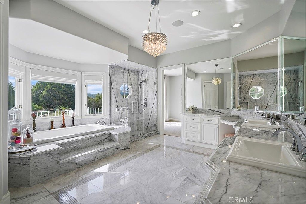 Primary bath in marble with bay-window tub at 22510 La Quilla Dr, Chatsworth